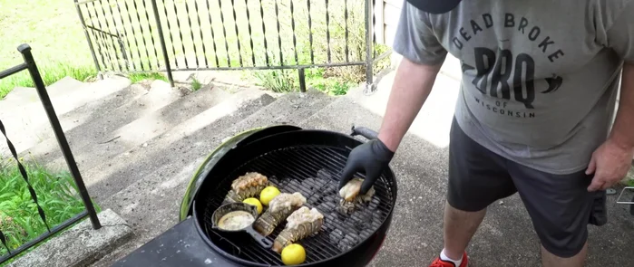 Grill the lobster tails (second stage). Move the lobster tails to a spot above the coals for more direct heat, and add more butter sauce. Grill the lemon halves.