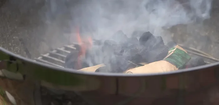 Light the paper: Light the bottom newspaper in a couple of spots. Allow flames to rise above the charcoal for good ignition.