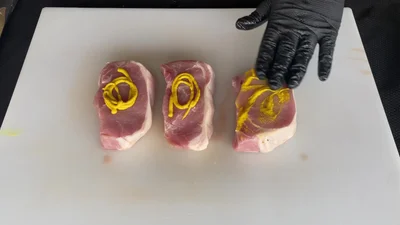 Season Pork Chops: Apply yellow mustard as a binder to help seasoning stick. Generously coat with your favorite barbecue rub.