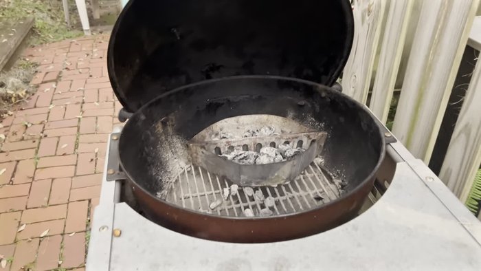 Add the reused charcoal to the grill, placing it around the fresh charcoal.