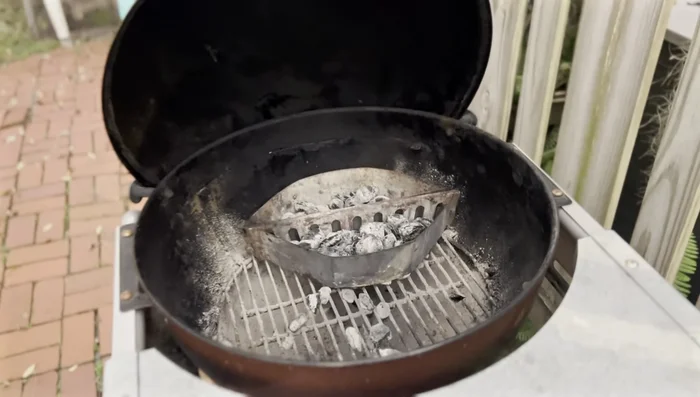Add the reused charcoal to the grill, placing it around the fresh charcoal.