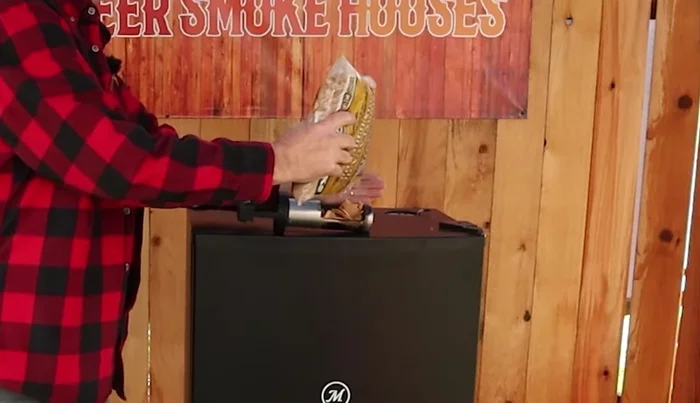 Pour approximately 1/2 cup of wood chips or chunks into the loading tube, guiding them in with your hand. Avoid overloading. The smaller the wood pieces, the faster they'll burn and the heavier the smoke will be.