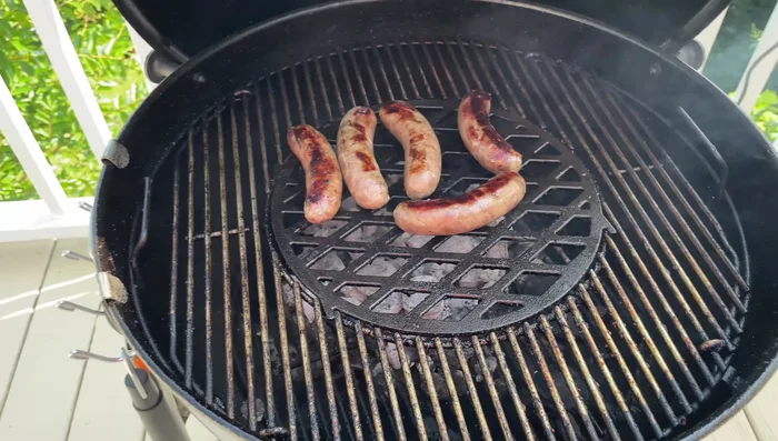 Weber grill with hinged grates and cast iron insert.