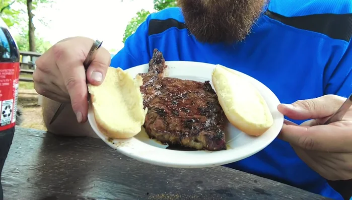 Grilled steak on a bun outdoors