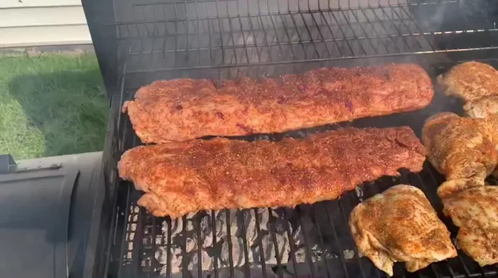 Large grill cooking ribs, chicken, and burgers.