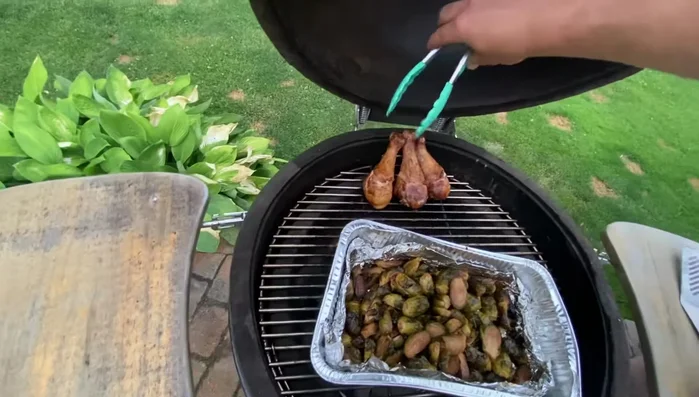 Komodo grill cooking chicken and brussels sprouts