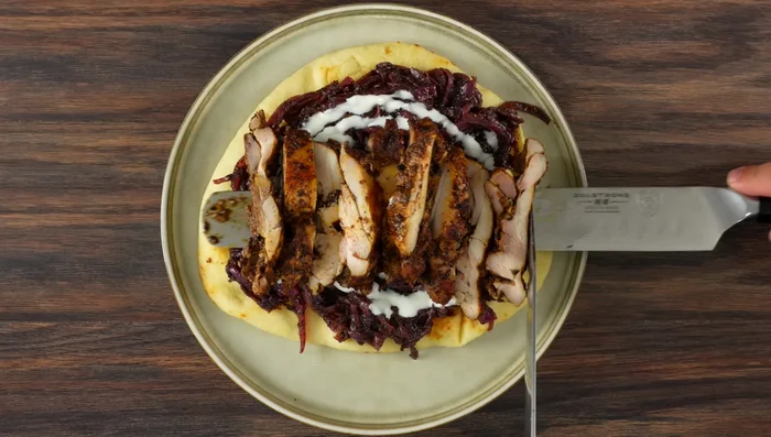 Assemble the chicken dish: Layer naan bread, caramelized onions, Mexican crema, chicken thighs, parsley, and olive oil.