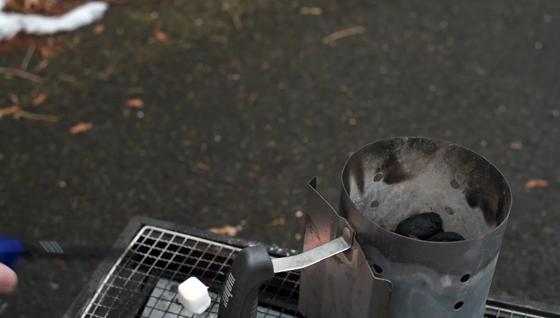 The reviewer lighting charcoal using a chimney starter.