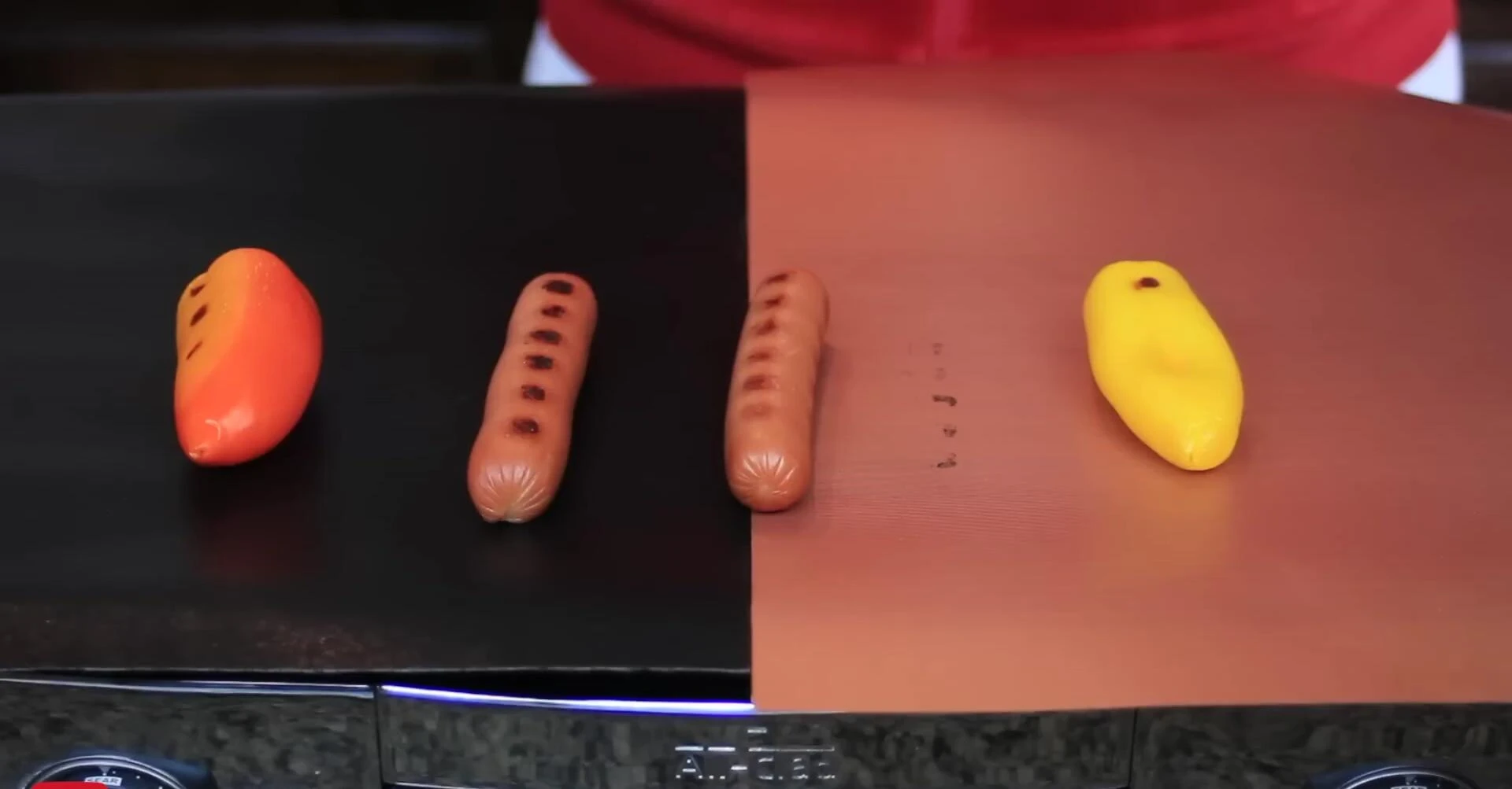 Hot dogs cooking on different mats, one moves.