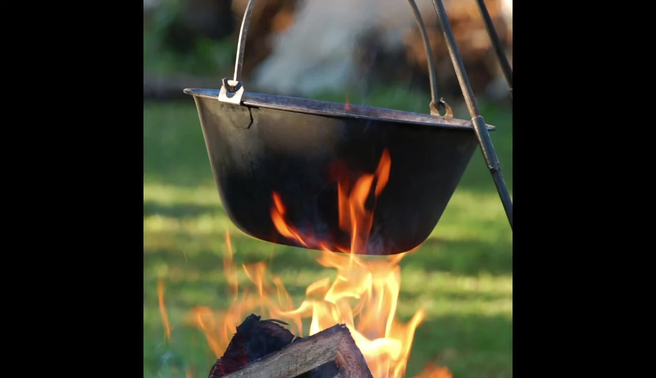 Pot hanging over campfire, heat resistant gloves needed.