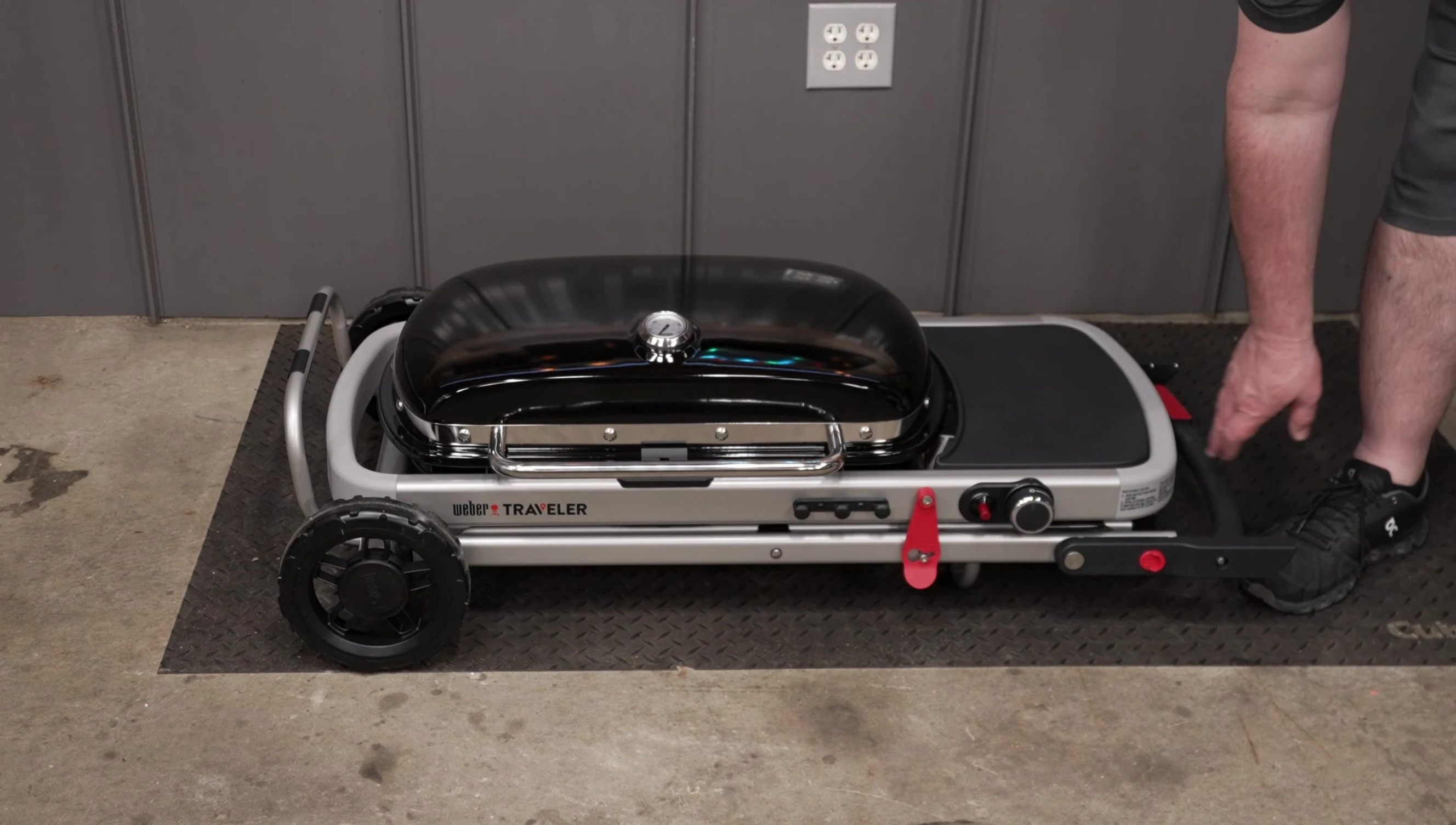 The grill with its large wheels being wheeled over different surfaces.