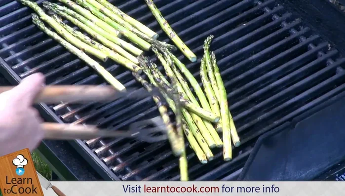 Turn asparagus and add fresh oregano to the grill.