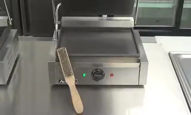 The removable grease tray and wire brush are displayed.