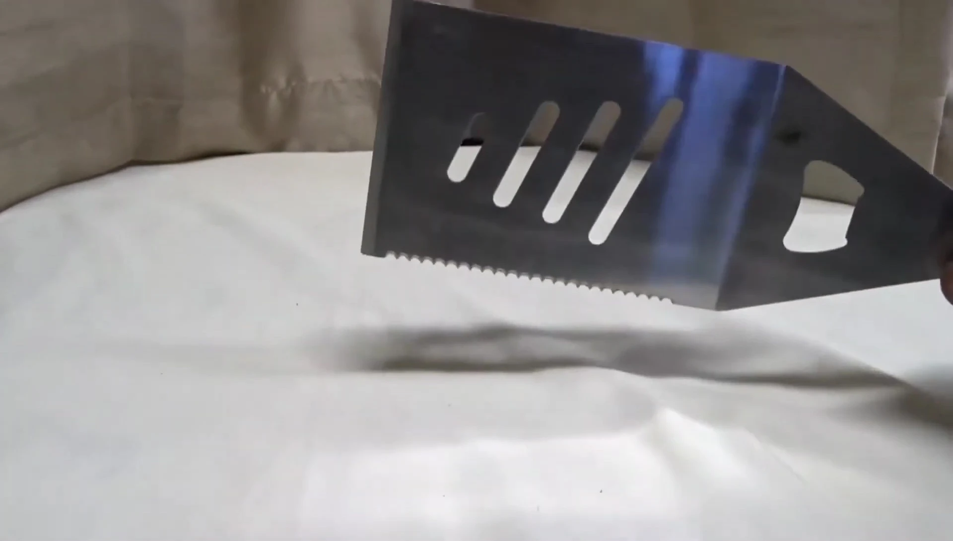 The reviewer points out the sharp edge as a key feature of the spatula.