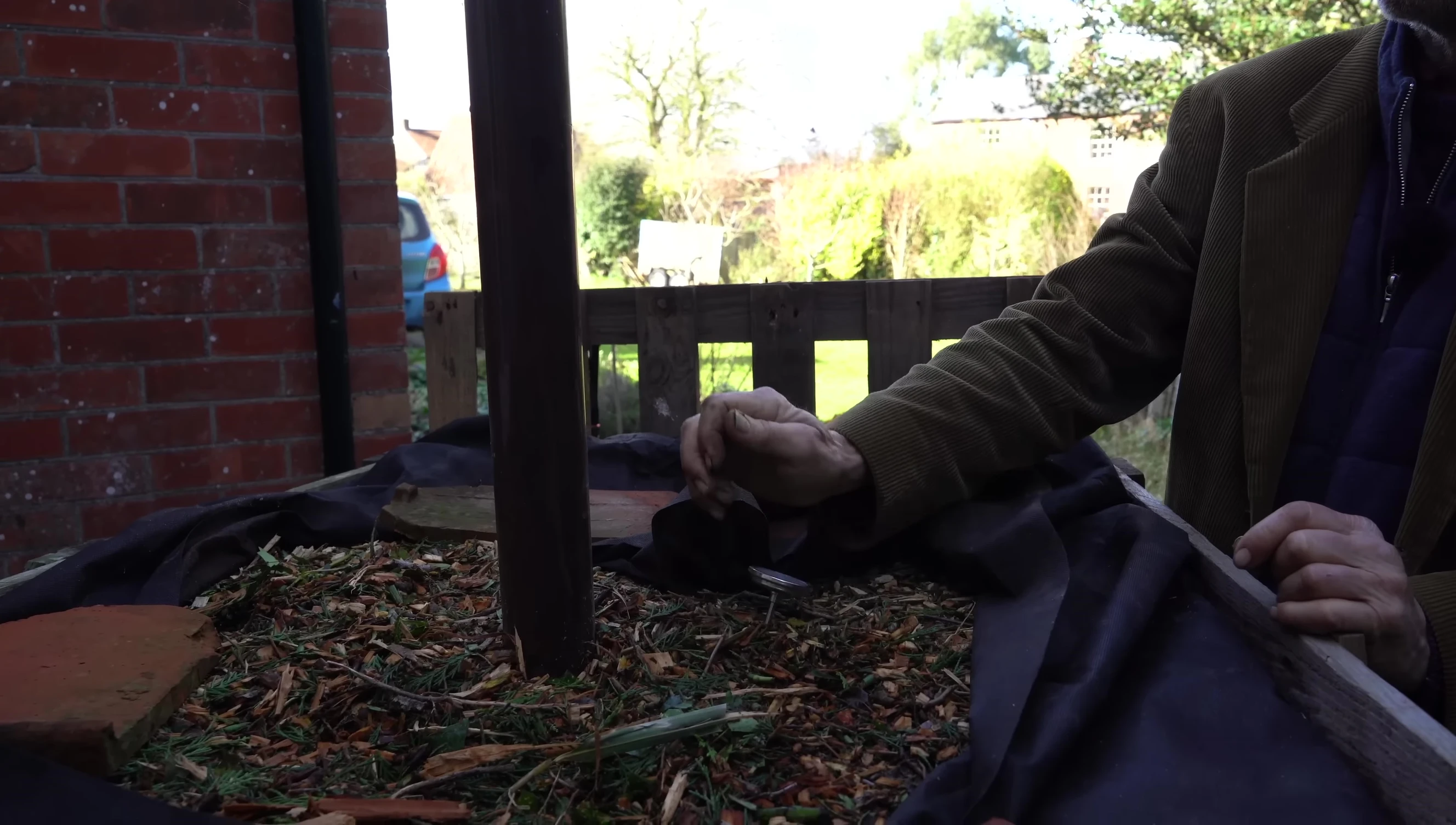 A wood chip compost heap built with a pallet base and air pipes.