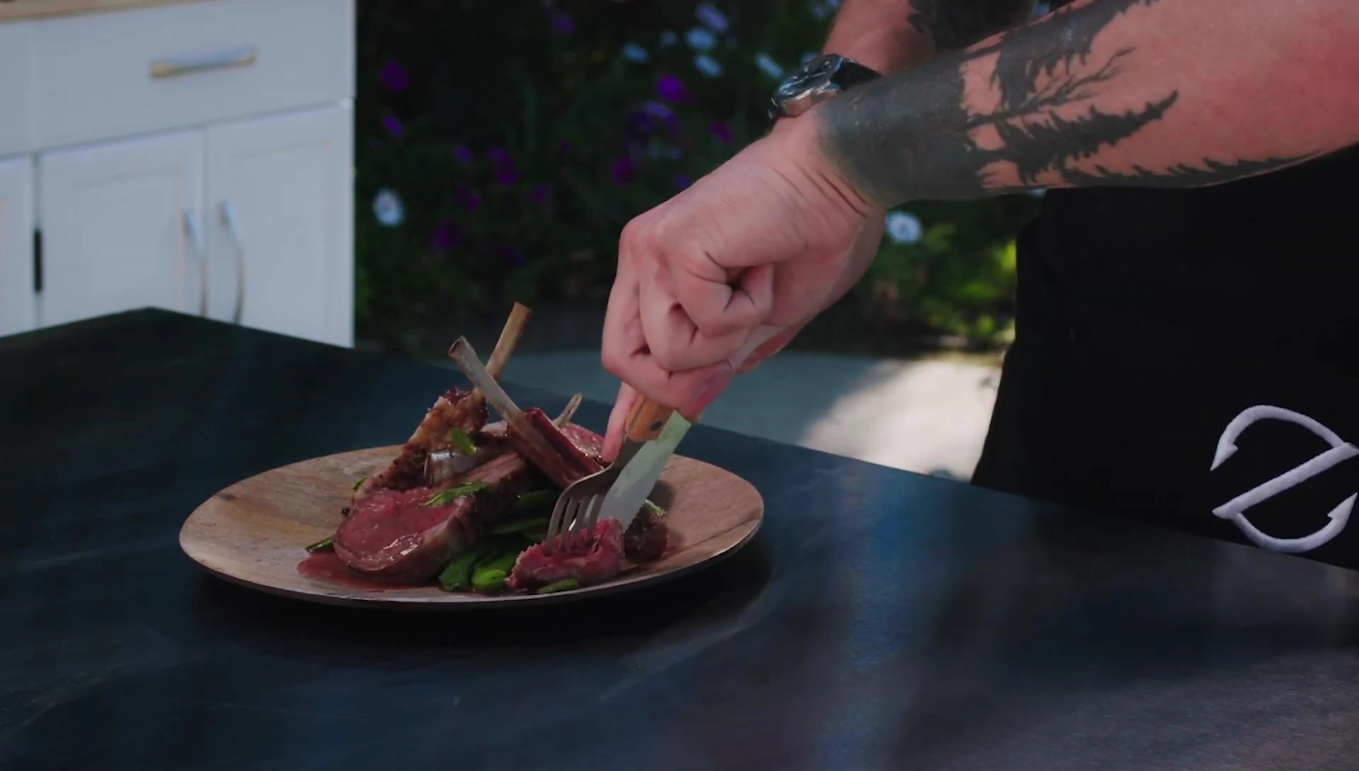 Plated smoked lamb rack with vegetables and sauce.