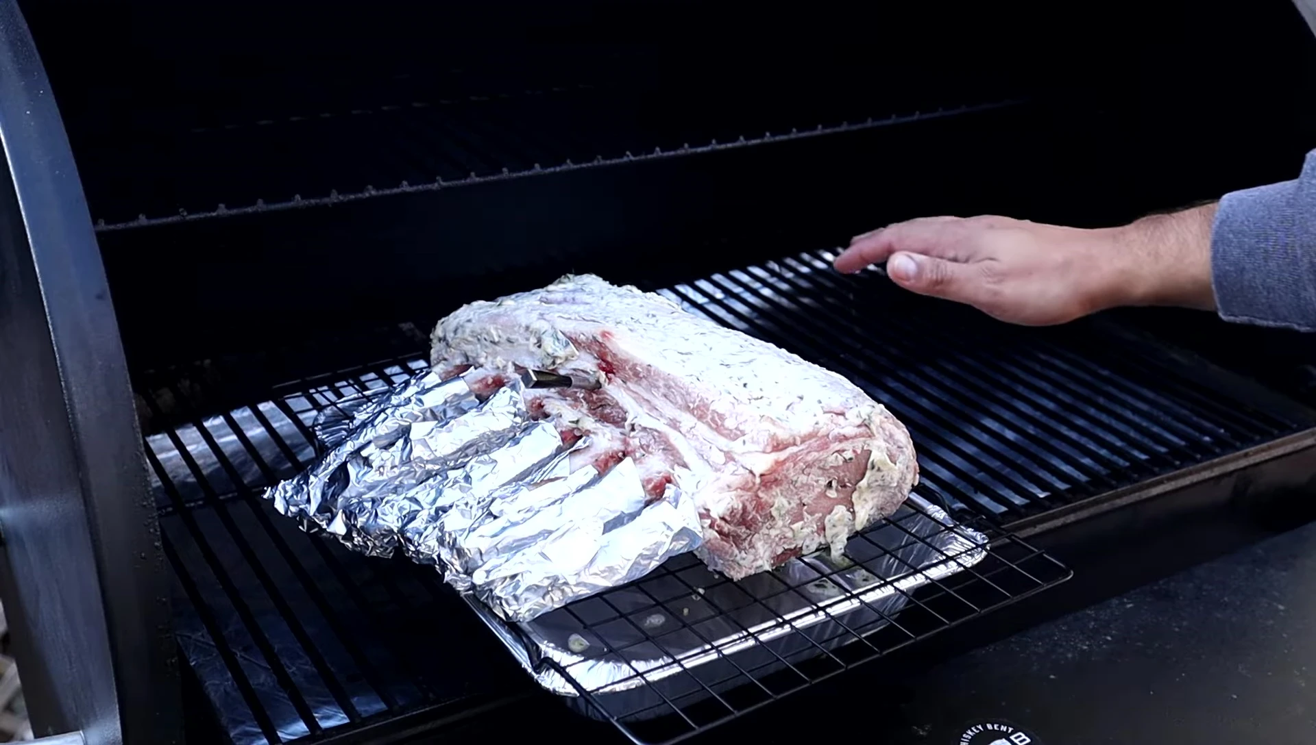 Inserting the meat thermometer into the pork rack.