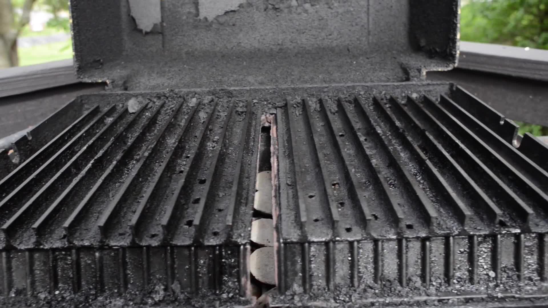 Close-up of heavily soiled grill grates, showing clogged holes and baked-on grease.