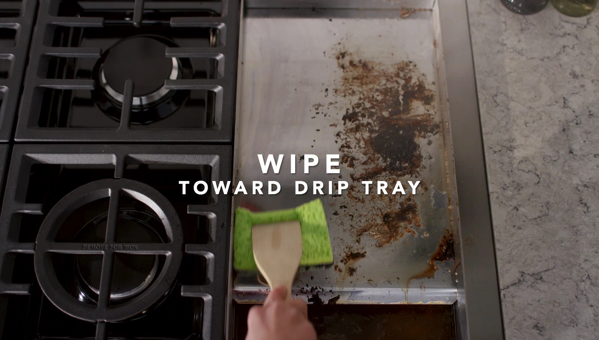 Cleaning the griddle surface with a sponge.