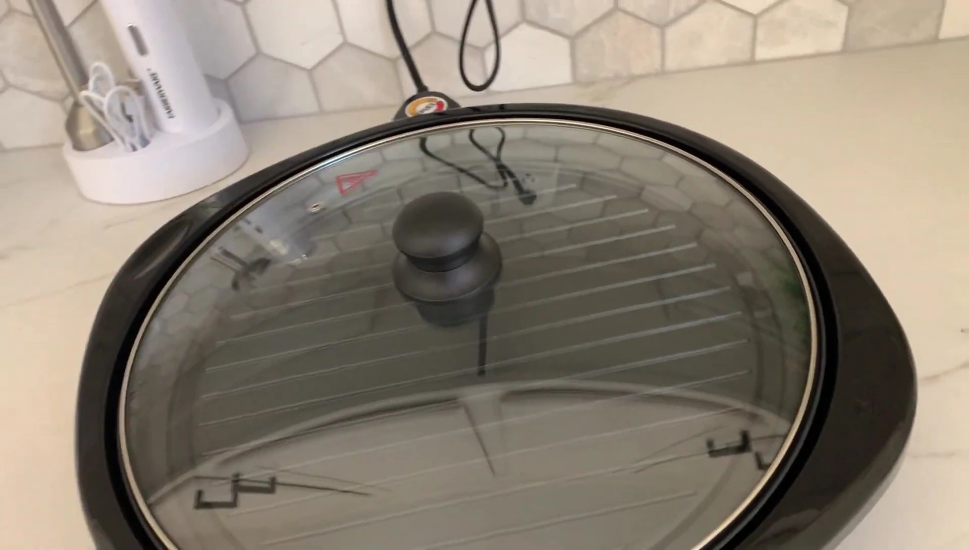 Close-up of the Elite Gourmet electric grill's compact cooking surface and removable cover.