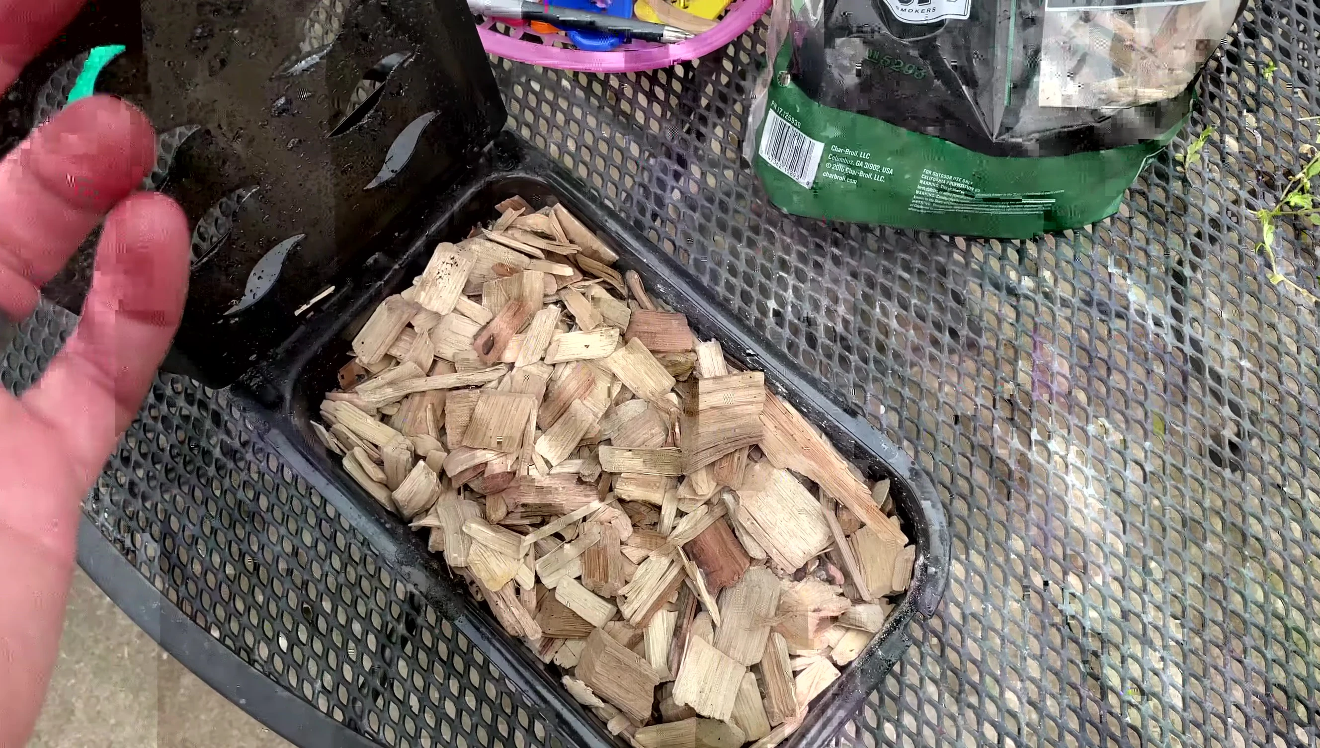 Close-up shot of the chef filling the Pit Boss wood chip smoker box.