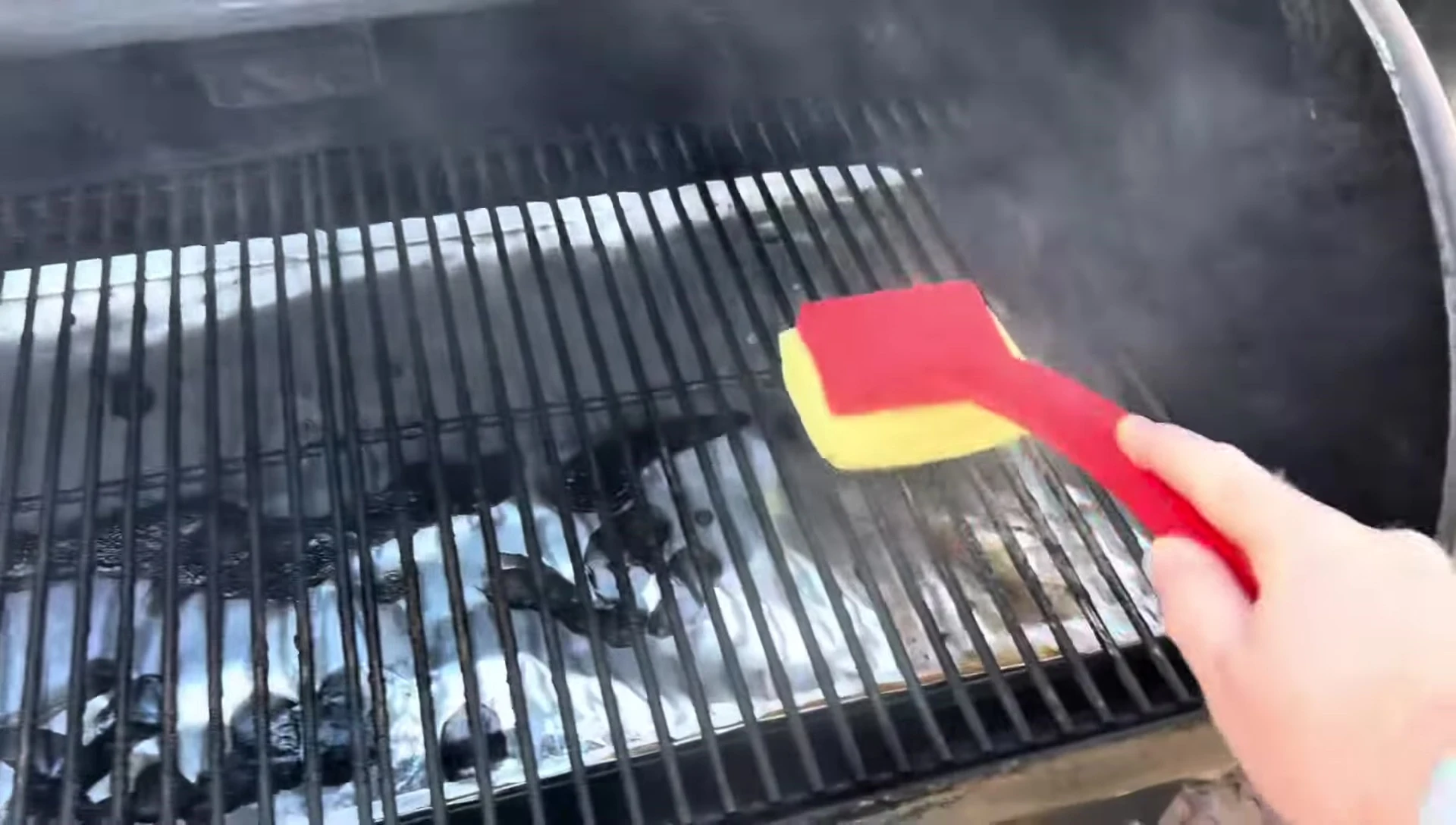 The user gently scrubbing the grill grates.