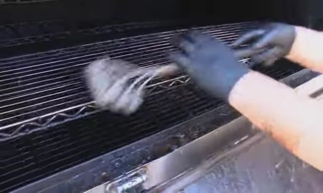 Showcasing the Kona Safe Clean brush's ability to navigate grill reinforcement bars.