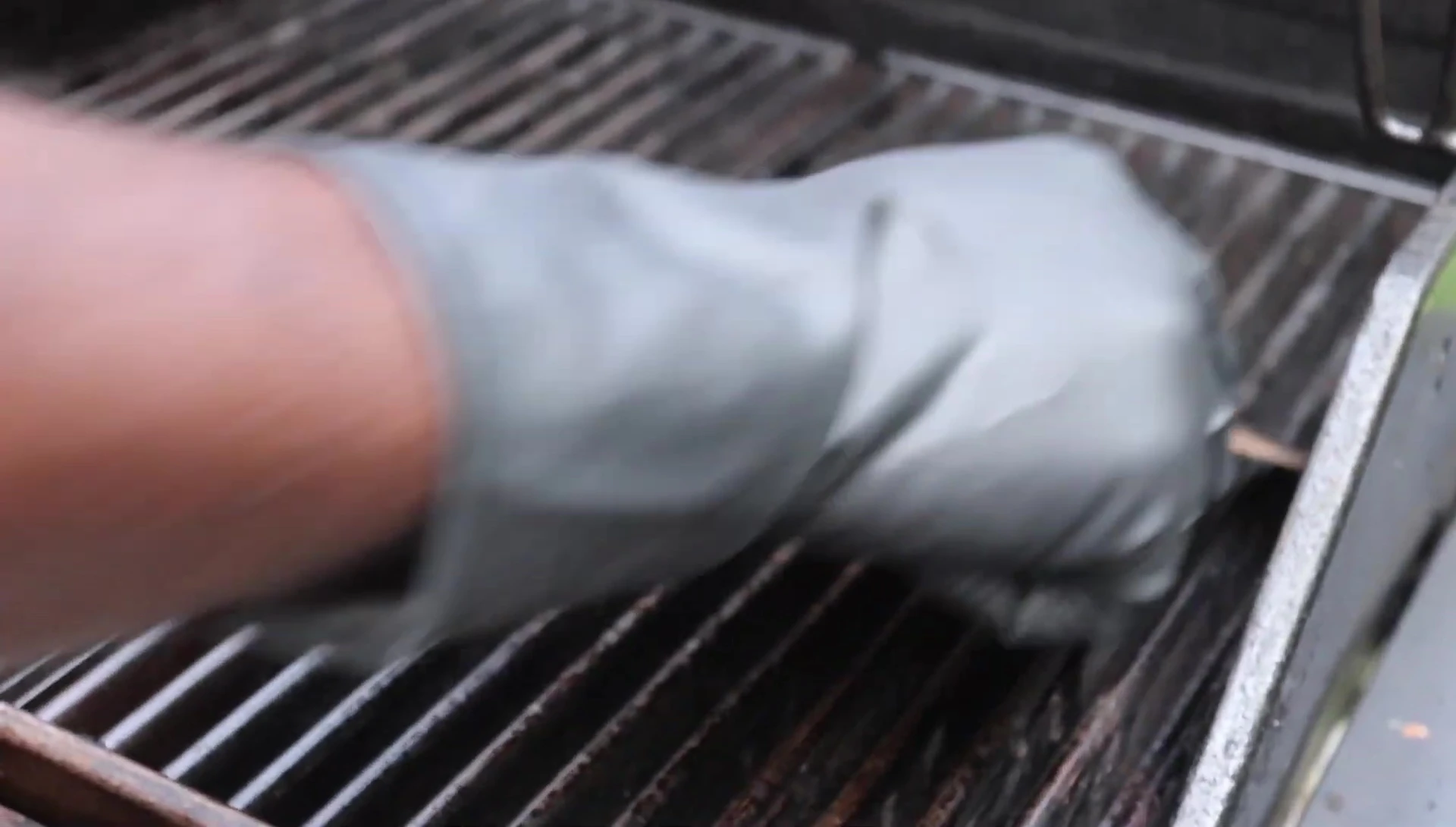Scraping loose debris from the grill grates