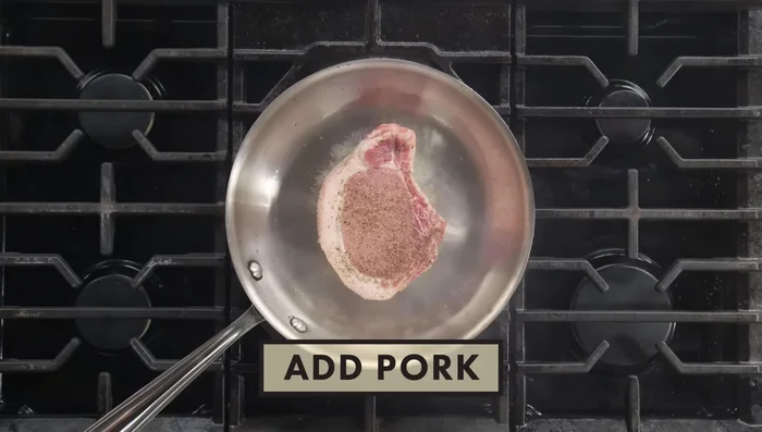 Once browned on both sides, sear the pork chop fat-side down to render the fat and reduce moisture.