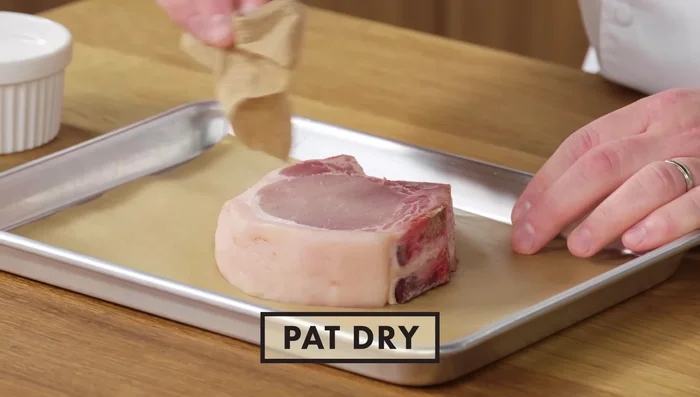 Season the pork chop generously with salt and pepper, ensuring both sides and the fat cap are seasoned. Pat dry to remove excess moisture.