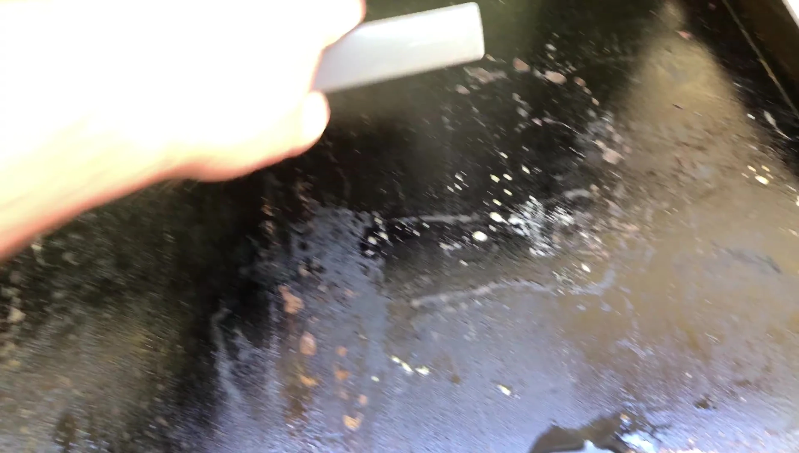 The reviewer is using the scraper to clean the griddle.