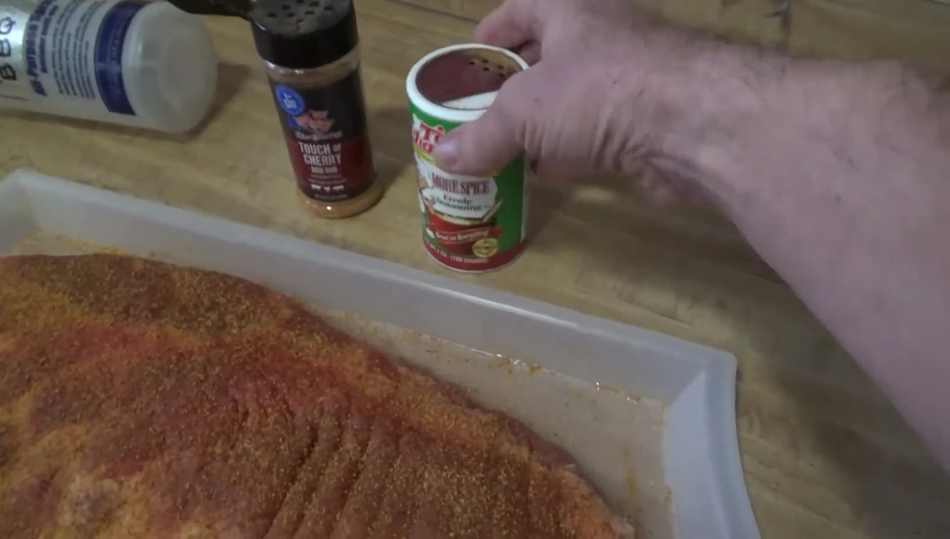 Seasoning being applied to the ribs.