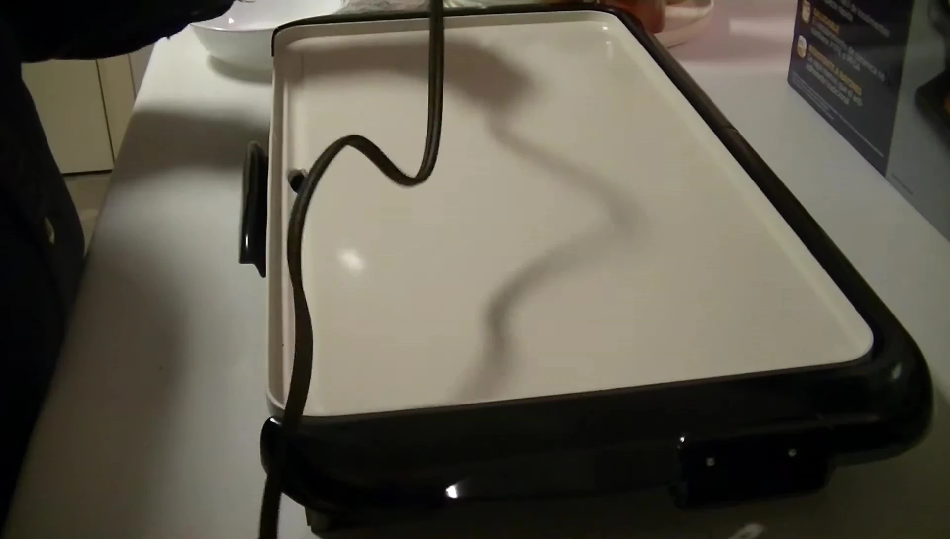 Shot of the reviewer plugging in the griddle, emphasizing the convenient cord length and placement.