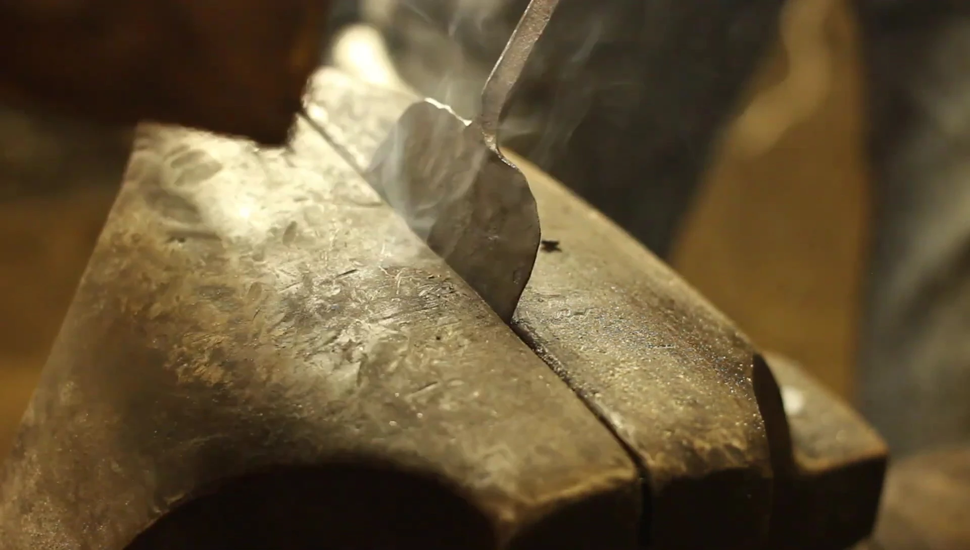 The smith bends the spatula to shape the handle.
