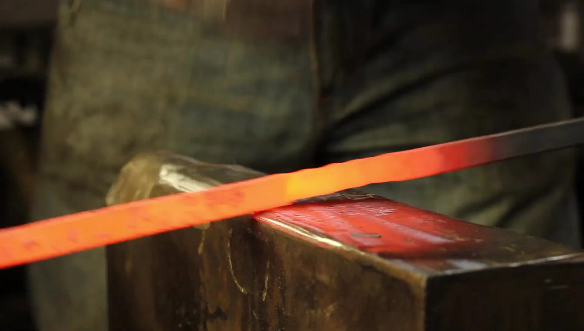 Close-up of the smith working the metal on the anvil.