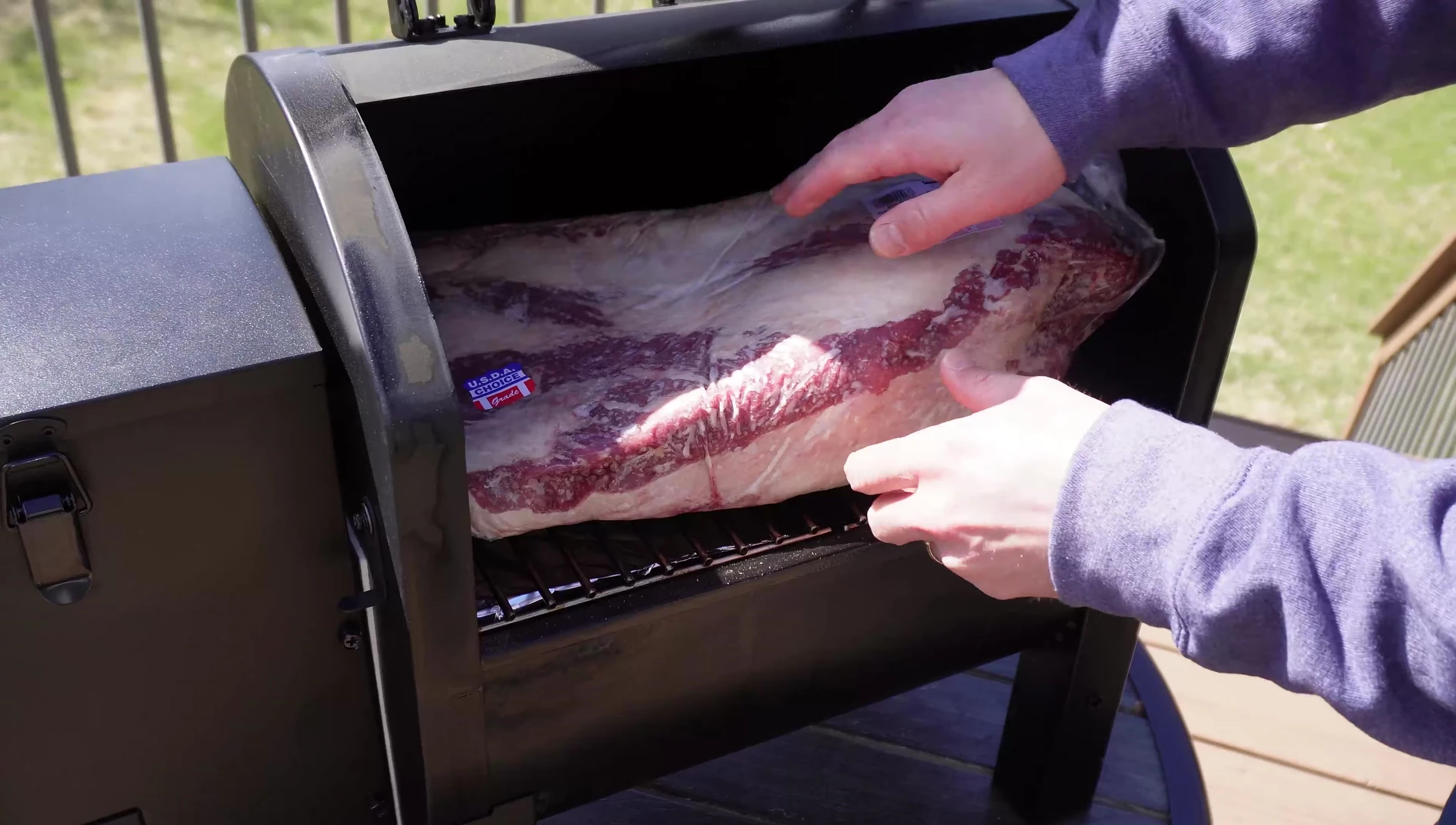 The brisket being placed inside the grill.