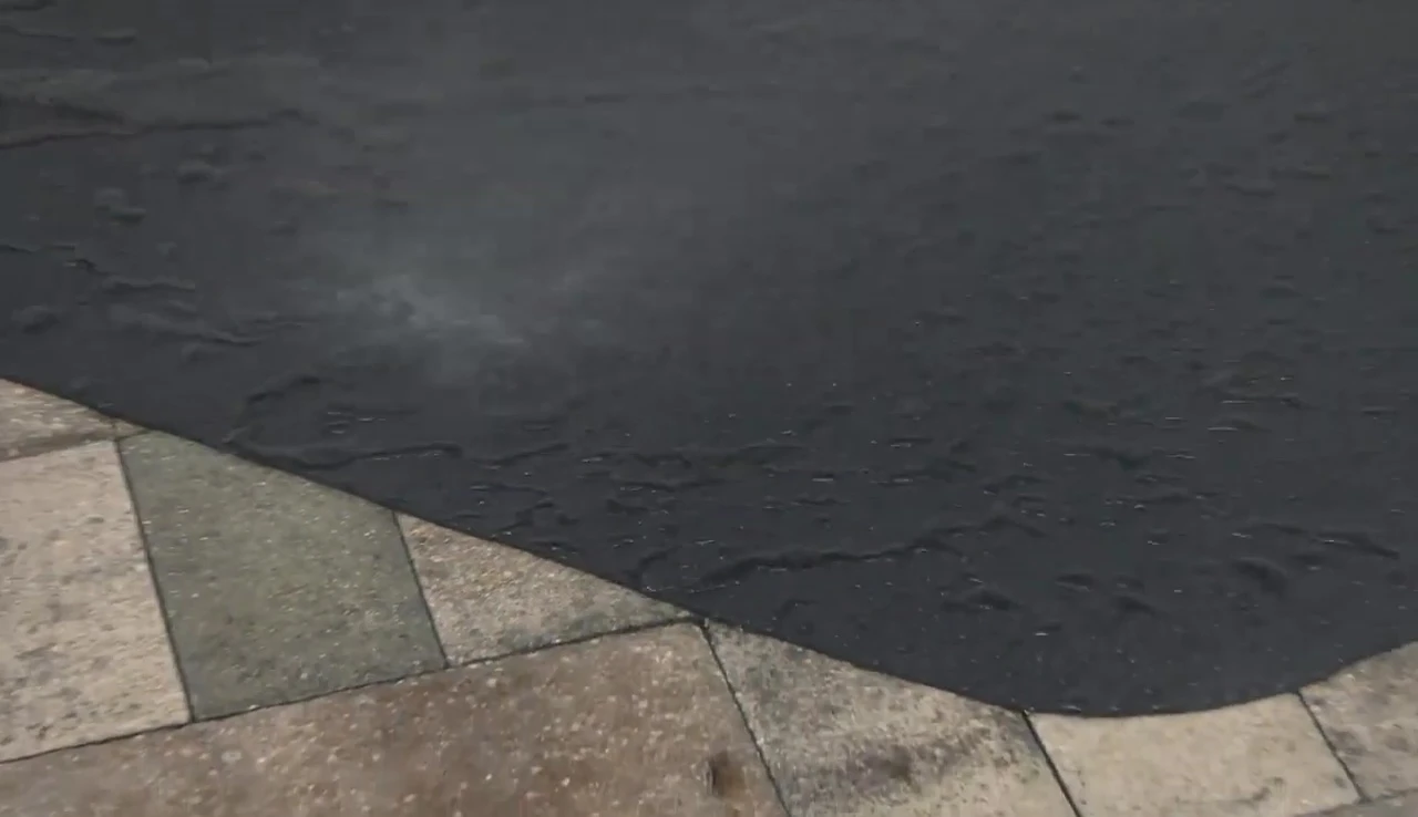 Someone hosing down the GrillTex Pro grill mat.