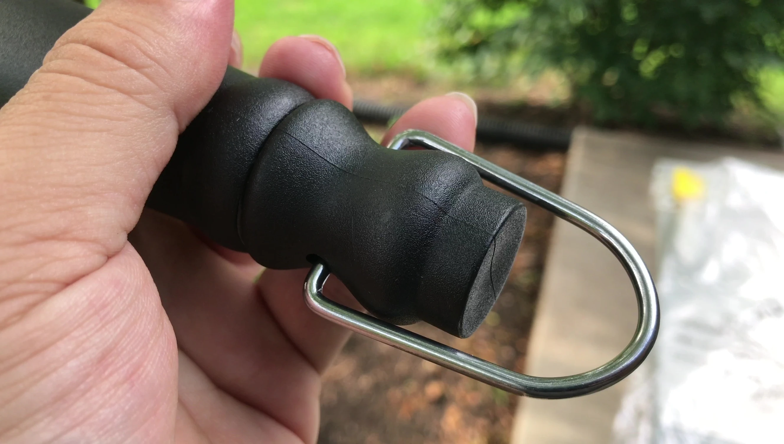 The grill brush showcasing its large steel D-ring for hanging.