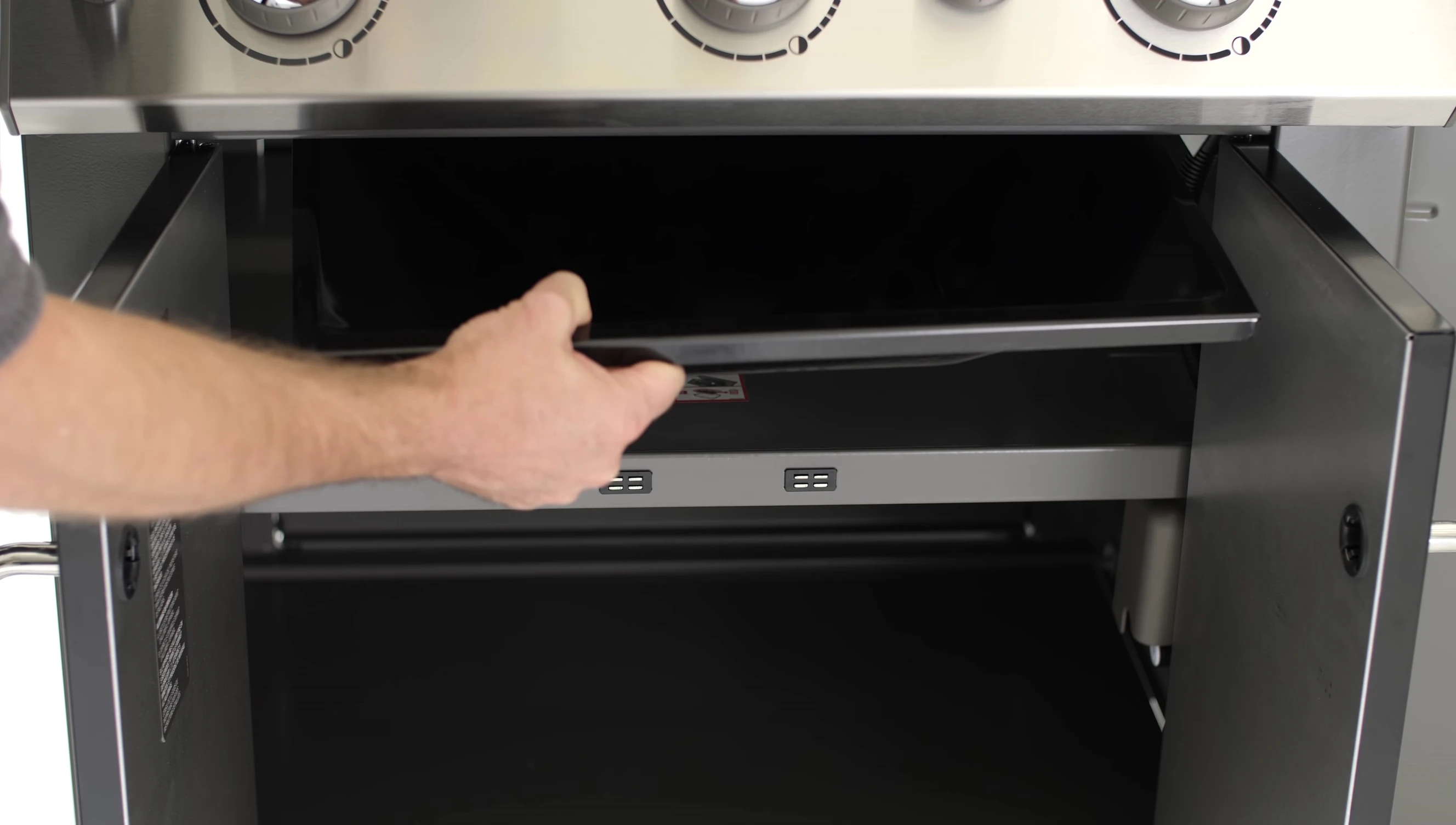 The grease tray being slid out for cleaning.