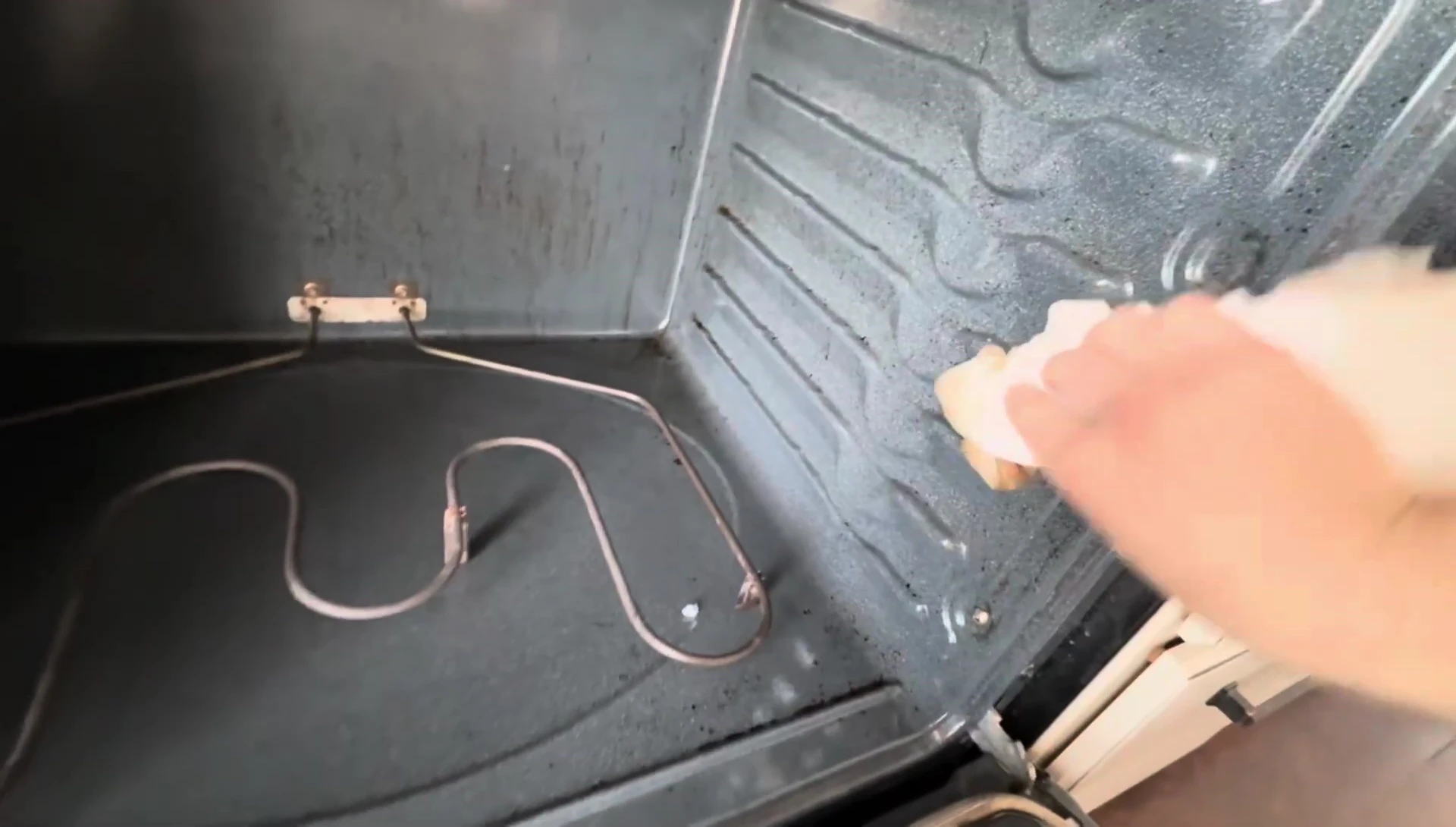 Wiping down the oven with a wet paper towel.