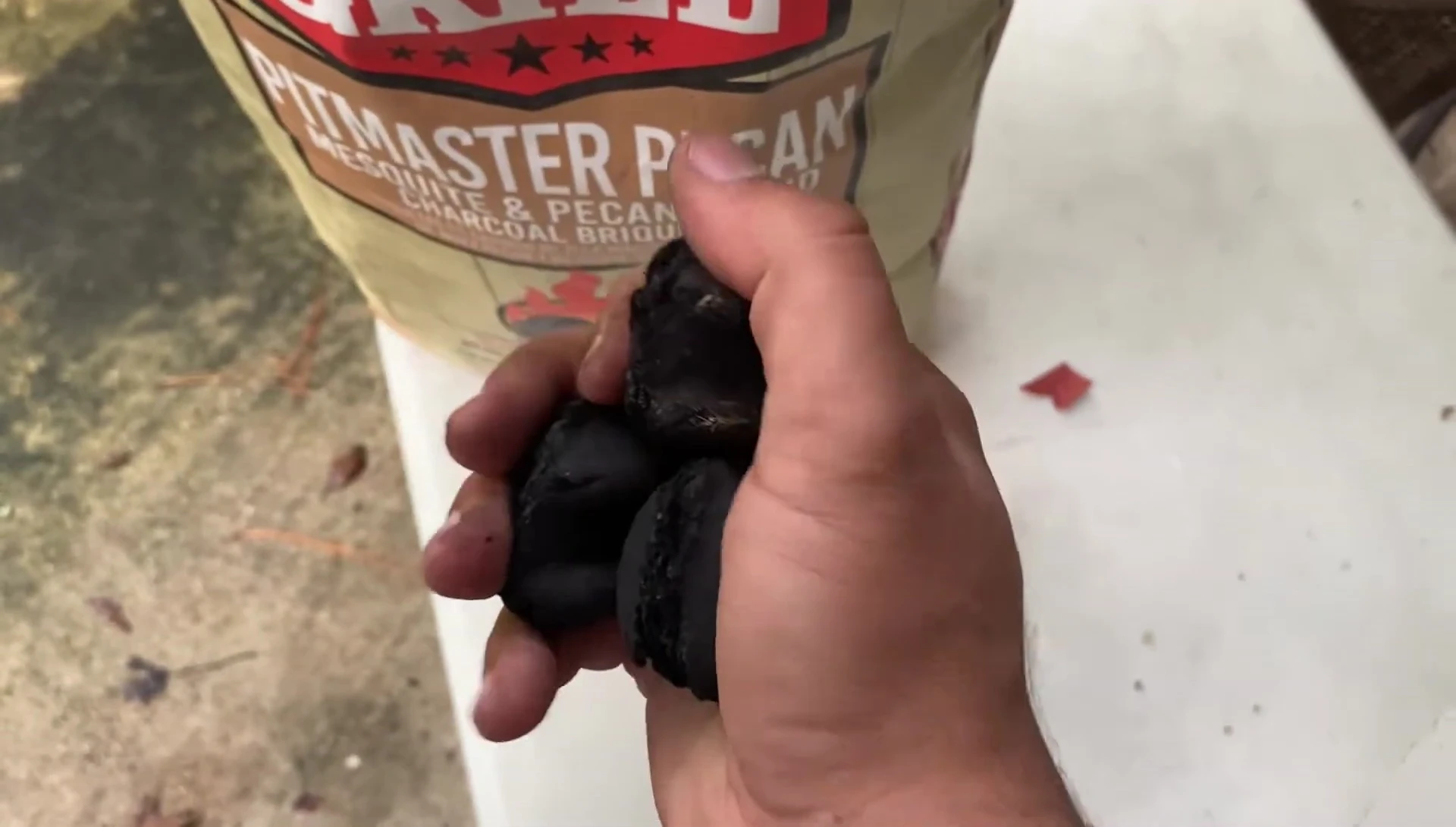 The reviewer pressing on a charcoal lump to test its durability
