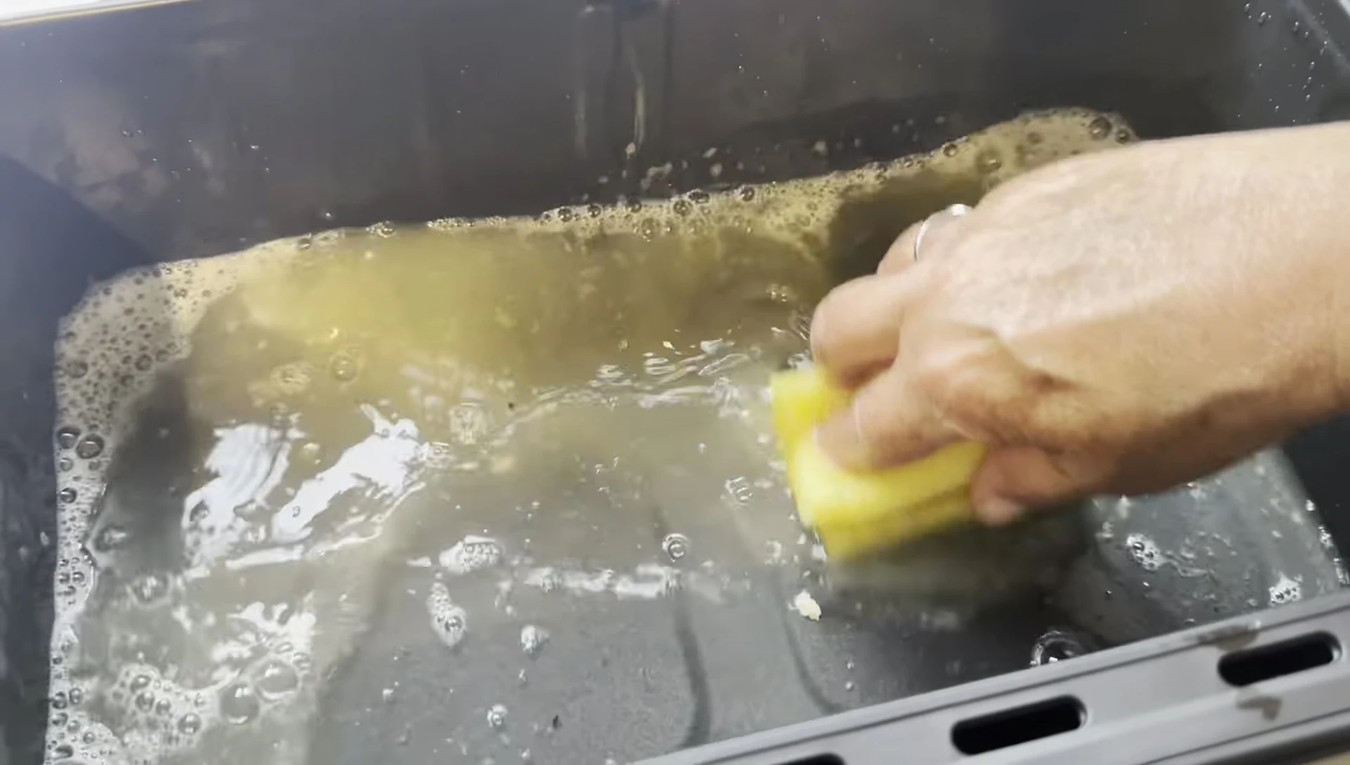 The air fryer tray being cleaned.