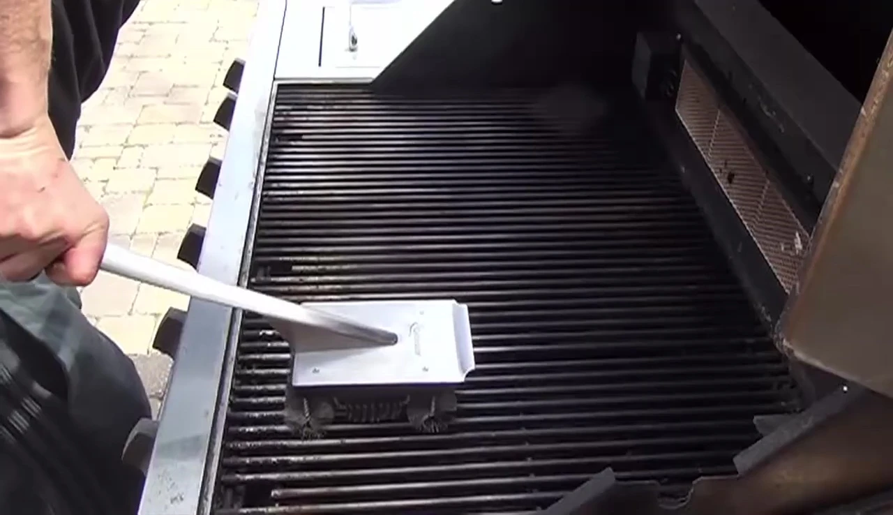 Close-up shot of the Grillinator brush, showcasing its stainless steel shaft and rubberized grip.