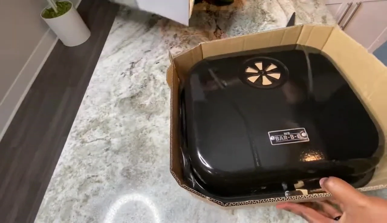 Close-up of the grill box being opened, revealing the heavy grill.